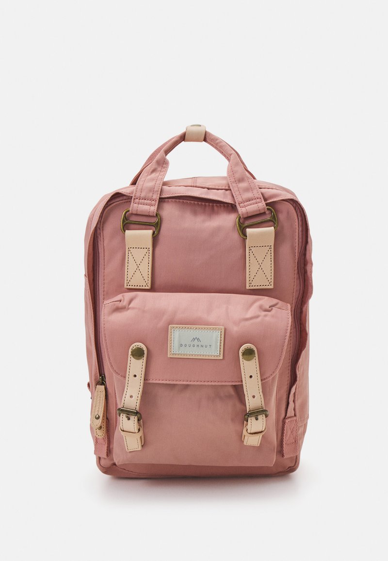 Pink fabric backpack with beige leather accents, dual side pockets, top handle, adjustable straps, and a front flap with a logo patch.