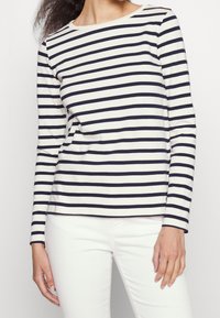 Langärmliges Jersey-Oberteil mit horizontalen Streifen in Marineblau und Weiß, rundem Ausschnitt und lockerer Passform. Weiche Textur ohne bemerkenswerte Muster oder Akzente.