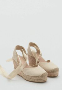 Bež espadrilice sa wedges potplatom s teksturiranim tkanim potpeticama, gornji dio od tkanine i odgovarajuće trake za sigurno pričvršćivanje. Zaobljeni vrh i meki završetak.