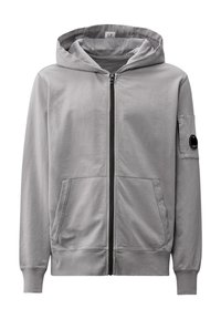 Lichtgrijze zip-up hoodie van zacht materiaal, met een voorrits, twee zijzakken en een ronde patch op de linkermouw.