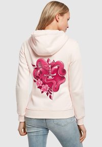 Felpa rosa chiaro con un design grafico prominente che presenta un serpente e un cuore, arricchito da elementi floreali e un pugnale. Tessuto morbido, vestibilità rilassata.