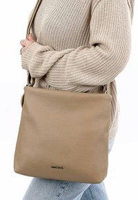 Beige Leder Crossbody-Tasche mit strukturierter Oberfläche, ausgestattet mit einem Akzent in silberner Farbe und einer geräumigen rechteckigen Form.