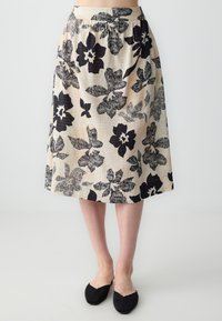 Beige bloemenrok met zwart bloemenprint, in een uitlopende stijl, met een middellange snit en een geraffineerde tailleband. Gemaakt om te dragen met zwarte platte schoenen.