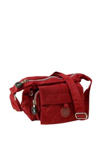 Red cloth crossbody bag with two zippered compartments, adjustable strap, and a front flap pocket featuring a circular logo.