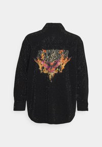 Camisa negra de botón con textura de puntos, que presenta un colorido diseño gráfico impreso en la parte trasera, mostrando llamas y texto.