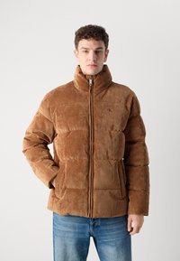 Braune Corduroy-Puffermantel mit hohem Kragen, Reißverschluss und zwei Fronttaschen; gestaltet mit vertikaler Rippstruktur.