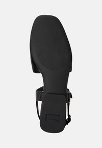 Schwarze Schuhsohle mit strukturiertem Grip und seitlichem Riemen. Das Design hat eine runde Form, die für legere oder formelle Anlässe geeignet ist.