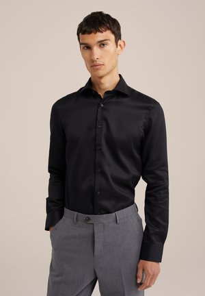 Cămașă neagră cu mâneci lungi și nasturi, cu o textură netedă, asortată cu pantaloni personalizați de culoare gri deschis, cu închidere frontală cu nasture.