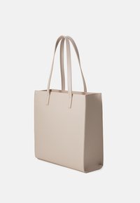 Beige tote bag med to lange håndtag, rektangulær form, glat tekstur og syning detaljer langs sømmene.
