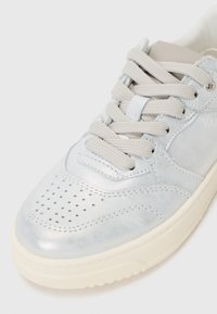 Baskets métalliques bleu clair avec un capuchon perforé, lacets beiges et semelle texturée. Présente un design minimaliste et un accent de marque.