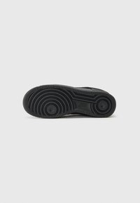 Fekete gumi sneaker talp kör alakú barázdákkal, textúrált bemélyedésekkel és két kör alakú kiemeléssel a tapadásért. Tartós és csúszásmentes kialakítás.