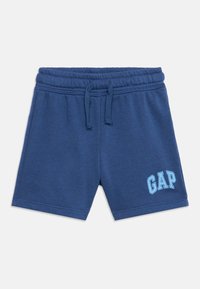 Pantalones cortos de algodón azules con cintura elástica, cordón ajustable y logo "GAP" en azul claro en la pierna izquierda.