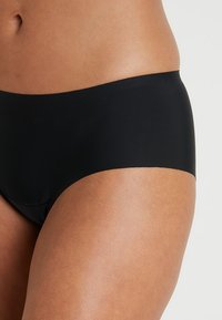 Black brief made from smooth, stretchy fabric. Features a high-rise design with clean edges and no visible hardware or patterns.
