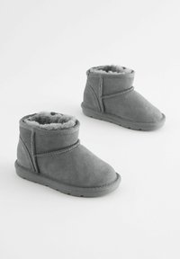 Graue Wildleder-Stiefeletten mit einem weichen Futter aus Fell, abgerundetem Zehenbereich und einem umlaufenden Riemendetail. Strapazierfähige Gummisohle für bessere Traktion.