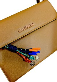 Clutch bag in pelle marrone con texture, tasselli intrecciati multicolori e charm a forma di cuore e cerchio in oro attaccati.