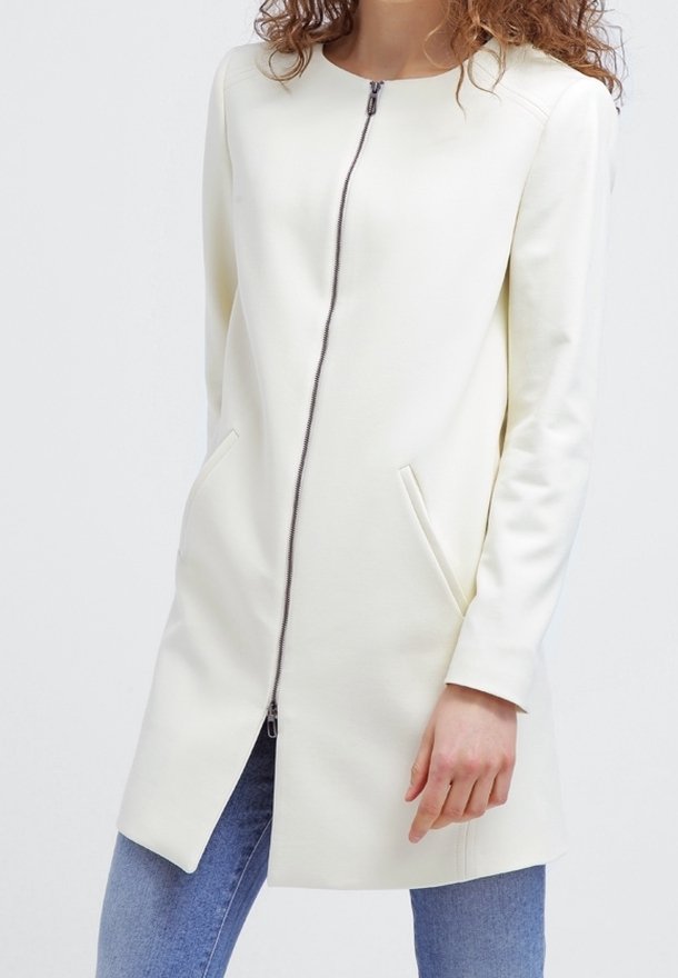 Vit zip-front kappa med rund halsringning, två sidfickor och en något strukturerad design. Slät textur, knälång och figursydd.