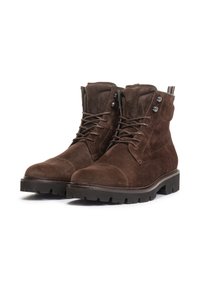 Bottes chelsea en suede marron avec un bout rond, un design à lacets et une semelle en caoutchouc dotée d'un profond relief pour l'adhérence ; accents en métal argenté sur les côtés.