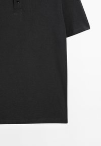 Černé polo tričko s texturovanou látkou, krátkými rukávy a límcem na tři knoflíky. Žádné vzory ani další akcenty nejsou viditelné.