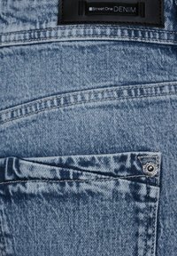 Jeans de mezclilla de color azul claro con una textura suave, que cuentan con un bolsillo trasero, costuras blancas y una etiqueta de tela negra con "Street One DENIM."