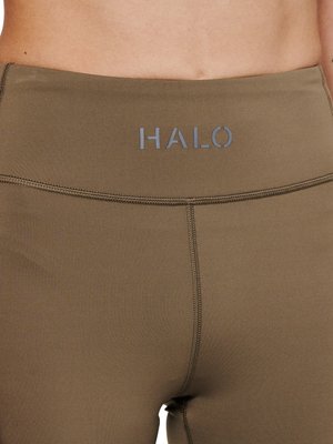 Close-up van bruine high-waist leggings met zichtbare naden en het "HALO"-logo in grijs gedrukt op de tailleband.
