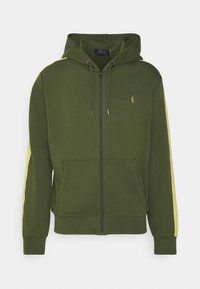 Grön zip-up hoodie med gula sidostycken, kängurufickor, snörningshuva och en liten broderad logotyp på bröstet.