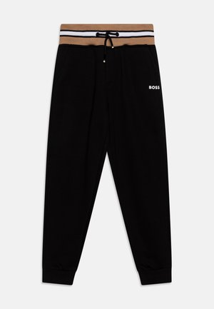 Pantalon de survêtement noir avec une ceinture élastique rayée marron et blanche, doté d'un cordon de serrage et du logo "BOSS" en blanc sur le côté.