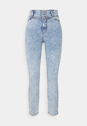 Jeans de denim azul de tiro alto con cierre de cinco botones, ajuste skinny y un lavado descolorido con sutiles detalles de desgastado y costura.