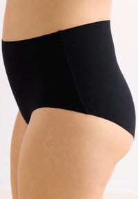 Zwarte high-waisted onderbroek met een gladde textuur en elastische tailleband, met een naadloos ontwerp voor een gestroomlijnde pasvorm.