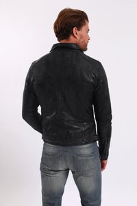 Zwart leren jack met een aansluitend ontwerp, voorzien van een staande kraag, achternaden en ritsmanchetten. Gecombineerd met vervaagde blauwe spijkerbroeken.