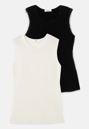 Dos camisetas sin mangas de punto suave, una blanca y otra negra, colocadas de manera plana con la camiseta blanca parcialmente superpuesta sobre la negra.