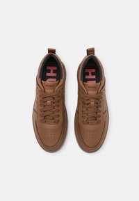 Baskets en cuir marron avec détails perforés, lacets plats et étiquettes de marque. Dotées d'une semelle intérieure rembourrée et d'une semelle en caoutchouc texturée.