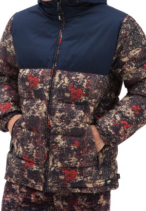 Gewatteerd jack met een marineblauw bovenstuk en een multicolor abstract patroon in rood, crème en donkere tinten; voorzien van een ritssluiting aan de voorkant en zijzakken.