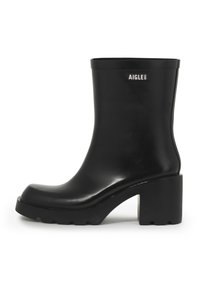 Black rubber ankle boot with a chunky heel, rounded toe, smooth finish, and a logo accent on the outer side. Textured sole for traction.