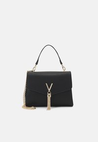 Bolso negro con un diseño estructurado, cadena dorada y un tassel decorativo. Presenta un destacado acento dorado en forma de 'V' en la parte frontal.