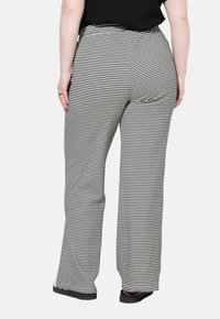 Zwart-wit gestreepte wijde broek met hoge taille en een gladde textuur, voorzien van een nette afwerking aan de zoom en zijzakken.