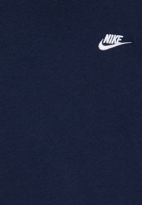 T-majica v mornarsko modri barvi iz bombaža z okroglim izrezom in majhnim belim vezene logotipom Nike na prsih, ki ima gladko in enostavno teksturo.