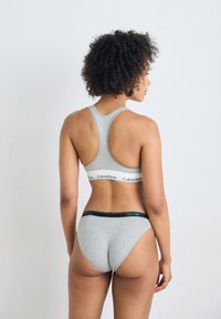 Grå bomullssportsbh med racerback-design og svart midjebånd; paret med matchende grå bikiniunderdeler med en fargerik logo på midjebåndet.