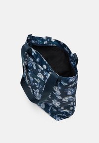 Granatowa torba na kwiaty z zamkiem błyskawicznym, wykonana z wytrzymałego materiału. Posiada miękkie uchwyty i czarne wzorzyste wnętrze. Wyeksponowane małe logo.