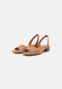 Sandali slingback in pelle color tan con una larga fascia frontale, punta quadrata e tacco basso a blocco. Texture liscia, design minimalista.