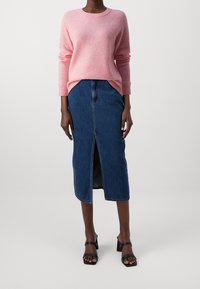 Růžový pletený svetr s dlouhými rukávy, ve spojení se středně dlouhou tmavou džínovou sukní s p�ředním rozparkem. Černé sandály na blokovém podpatku.