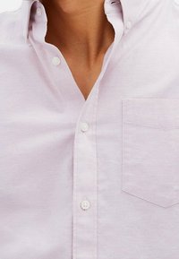 Camicia button-up viola chiaro in cotone con una texture liscia. Presenta una tasca sul petto e un colletto classico con bottoni bianchi.