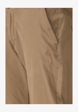 Pantalon beige avec une poche latérale et un logo triangulaire subtil cousu près de la poche, mettant en valeur la texture du tissu décontracté et les détails de couture.
