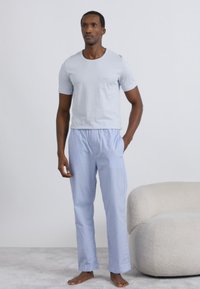 Vaaleanharmaa, lyhythihainen t-paita yhdistettynä sinisiin ruudullisiin pyjamahousuihin. Pehmeä kangas; rento istuvuus; housuissa joustava vyötärönauha.