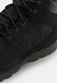 Botas de senderismo negras hechas de piel premium, con acentos texturizados, cordones duraderos y un logotipo destacado, además de una suela de goma resistente.