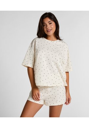 Crème-kleurige loungewear set met een T-shirt met korte mouwen en shorts, beide bedrukt met zwarte stippen. Zacht materiaal en een ontspannen pasvorm.