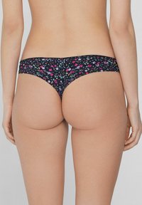 Czarny thong w kwiatowy wzór w różowym, niebieskim i zielonym kolorze. Miękka tkanina o gładkiej fakturze, z szerokimi bocznymi paskami dla wygody.