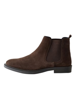 Brauner Chelsea-Stiefel aus Veloursleder mit schwarzem elastischem Seitenteil, Zuglasche hinten und schwarzer Sohle in Seitenansicht auf weißem Hintergrund.