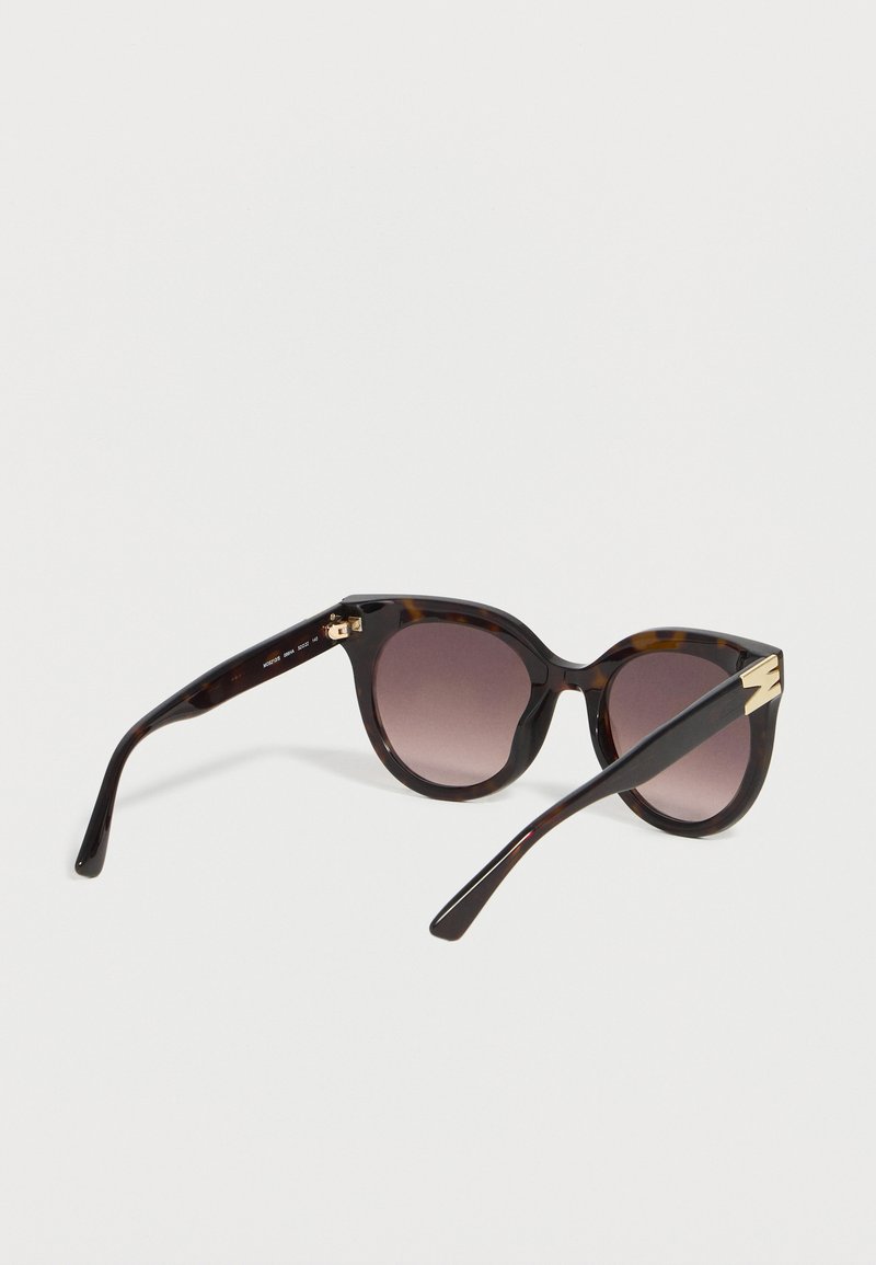 Tortoiseshell cat-eye sunglasses with dark gradient lenses and gold lightning bolt detail on the temple tips.
