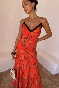 Punane lilleline kleit, millel on sobiv bodice, pitsist ääris ja laienev seelik. Mustad aktsendid ning erksad roosid koos roheliste lehtedega.
