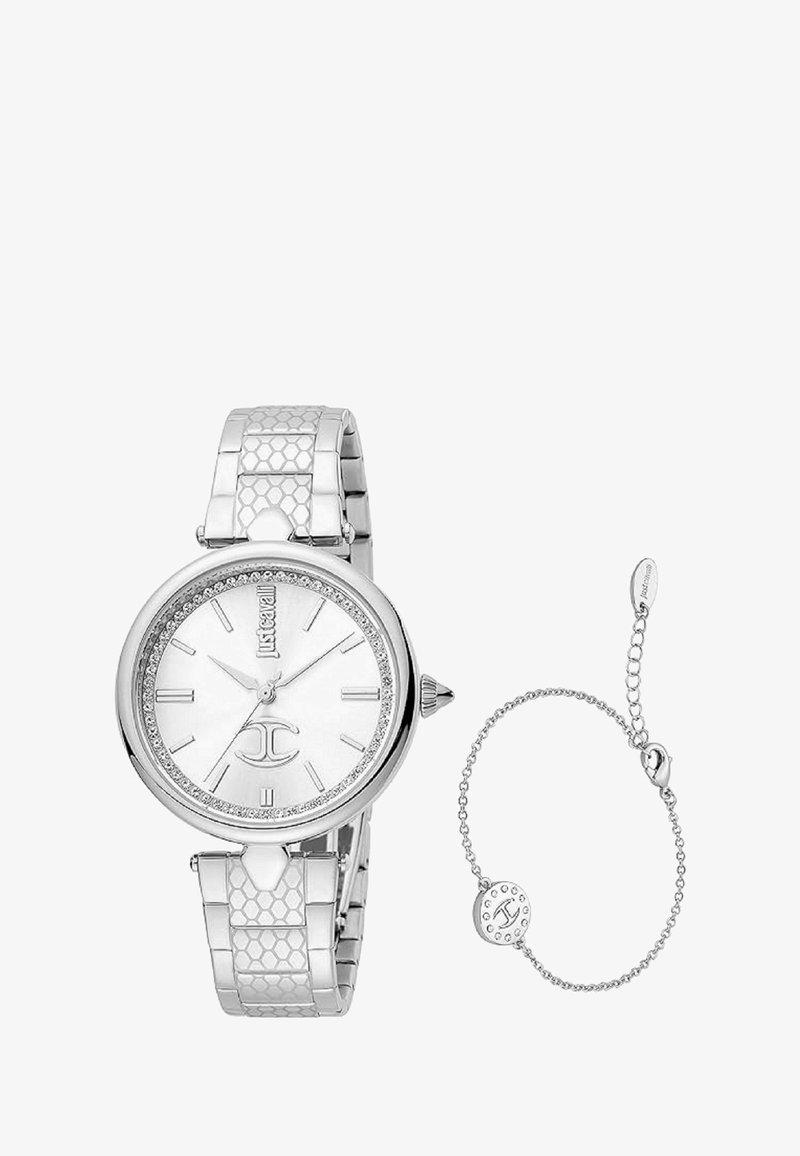 Hõbedane kell ümmarguse näo, valge dials ja kristallaktsentidega. Omab tekstuuriga metallist rihma. Sisaldab sobivat ketirihma.